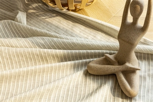 Close-up of cream cotton linen fabric with vertical stripes and natural fringe textures
