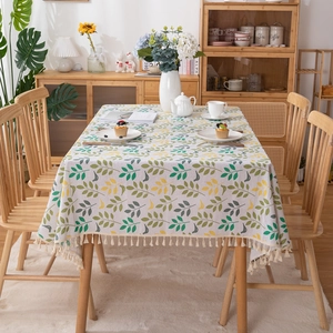 Rectangular leaf print tablecloth with tassels on a wooden dining table in Nordic style