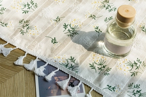 Detail of floral embroidery and handmade tassels on white cotton fabric door curtain