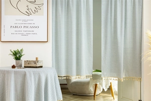 Detail of blue and white striped cotton door curtain with beige decorative tassels
