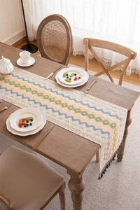Detail of bohemian geometric wave table runner with fringe tassels on dark wood table