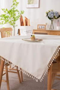 Close-up of cream PVC tablecloth with elegant tassel edges and minimalist design