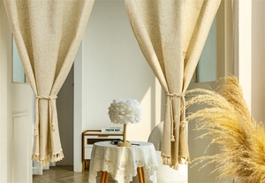 Detail of beige linen door curtain featuring natural texture and tassel fringe edges