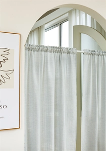 Detail of blue and white striped cotton cafe curtain with fringed edges on archway