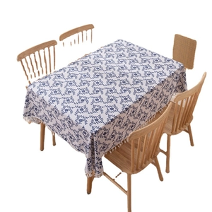 Rectangular tablecloth with blue floral print and white tassels on a wooden dining table