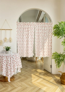 Close-up of strawberry print cotton door curtain featuring white pom-pom fringe details