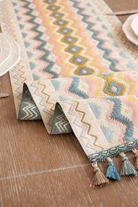 Close-up of geometric jacquard table runner with bohemian patterns and colorful tassels