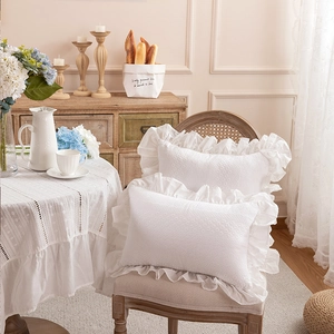 Detail view of white cotton pillowcase with embroidered eyelet and ruffled edges
