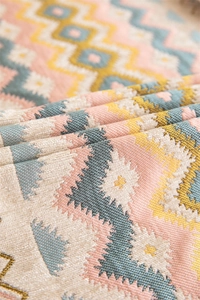 Detail of bohemian jacquard table runner featuring geometric wave patterns and fringes