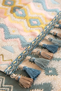 Detailed view of colorful jacquard table runner with geometric weave and blue tassels