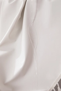 Close-up of white waterproof PVC tablecloth fabric showing water droplets and fringe detail