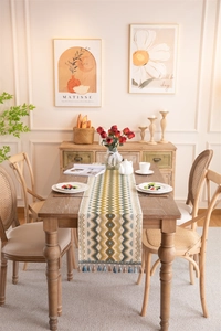 Close-up of geometric jacquard table runner with yellow ripple pattern and soft tassels