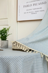 Detailed close-up of light blue striped cotton fabric with lace trim and tassel fringe
