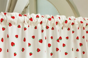 Detail of white cotton door curtain featuring red strawberry prints and rod pocket design
