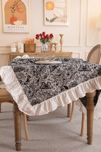 Close-up of vintage black butterfly pattern tablecloth with white ruffled edges