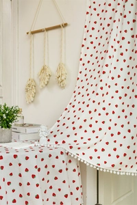 Close-up of cotton door curtain featuring red strawberry prints and white pom-pom trim