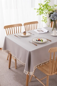 Detailed view of gray waterproof PVC tablecloth with decorative cream-white tassels