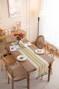 Close-up of geometric woven table runner with blue pom-pom tassels in a home setting
