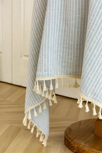 Close-up of light blue striped cotton linen tablecloth with cream decorative fringe