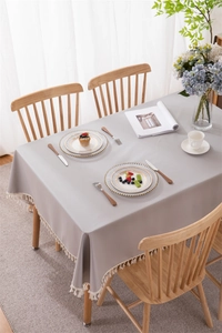 Detail of light grey waterproof PVC tablecloth featuring white fringe tassel edges