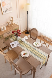 Detail of woven table runner featuring yellow and blue wave patterns with dark tassels