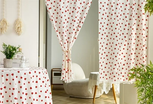 Close-up of strawberry print cotton fabric with white pom-pom tassel trim detailing