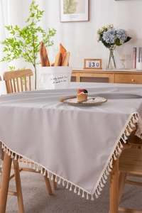 Close-up of light gray waterproof PVC tablecloth featuring delicate white tassel edges