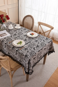 Close-up of vintage butterfly jacquard tablecloth with black fringe tassels and ruffles