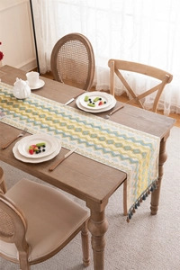 Detail of woven jacquard table runner with blue wave pattern and rustic tassels