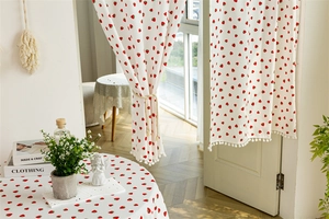 Detail of white cotton curtain with red strawberry print and delicate pompom fringe trim