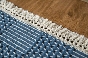 Vue rapprochée de la nappe jacquard géométrique bleue avec franges blanches et texture