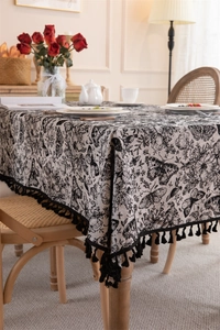 Detailed view of vintage black and white butterfly floral tablecloth with fringe tassels