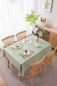 Detailed view of sage green PVC tablecloth with elegant white fringe tassel trim edge