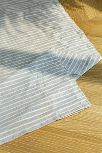 Detail of blue and white striped cotton fabric with neat stitching on wooden floor