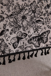Detail of vintage jacquard tablecloth featuring black floral butterfly motifs and fringe