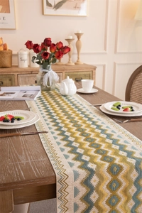 Detail of geometric wave jacquard table runner with decorative tassels on wooden table