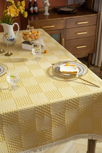 Vue détaillée de la nappe à carreaux jaunes et blancs avec pompons élégants
