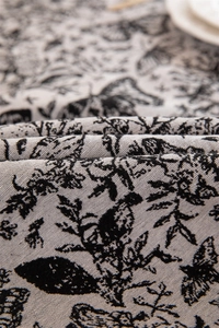 Close-up of black butterfly toile pattern on vintage cream jacquard tablecloth with ruffles