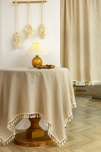 Detailed view of beige striped cotton door curtain with dense white fringe tassels