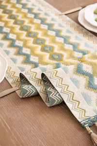Close-up of geometric wave jacquard table runner with decorative fringe on wooden table