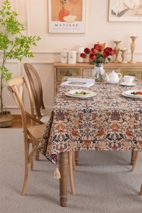 Detailed view of vintage jacquard tablecloth with floral bird patterns and tassel fringe