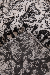 Close-up of vintage black and white butterfly jacquard fabric with tassels and ruffles