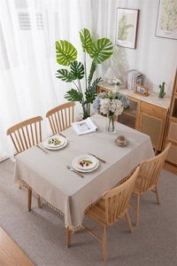 Detail of light beige cotton-linen tablecloth with tassel edge and woven stripe texture