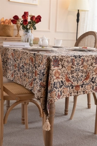 Close-up of vintage floral jacquard tablecloth with elegant cream fringe tassels