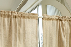 Detail of beige cotton linen door curtain with vertical stripes and rod pocket design