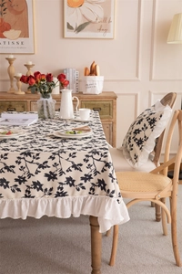 Detail of French vintage floral polyester tablecloth with ruffled edges and botanical prints
