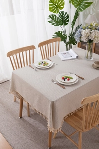Detail of beige jacquard cotton tablecloth with textured stripes and fringe tassels