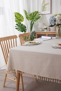 Detailed close-up of cream cotton jacquard tablecloth texture with elegant tassel fringe