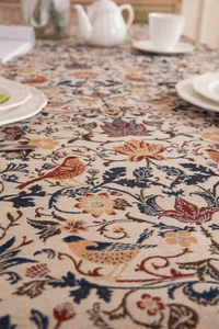 Close-up of vintage jacquard tablecloth featuring floral bird patterns and elegant fringe