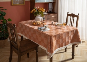 Détail de nappe à carreaux orange avec tissage texturé et bords à franges blanches